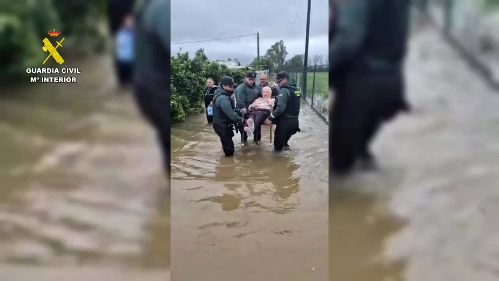 Agentes trasladan a una mujer a trav&eacute;s de una zona inundada.